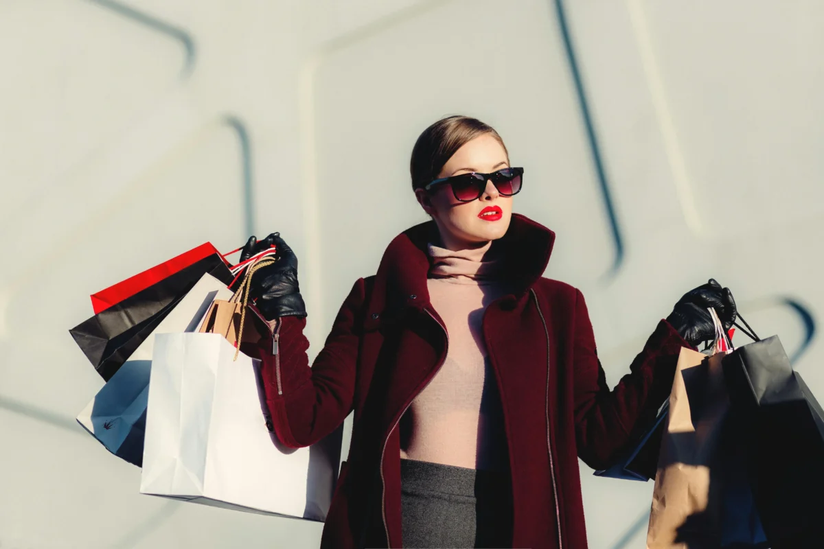 Fashionable woman carrying multiple shopping bags outdoors